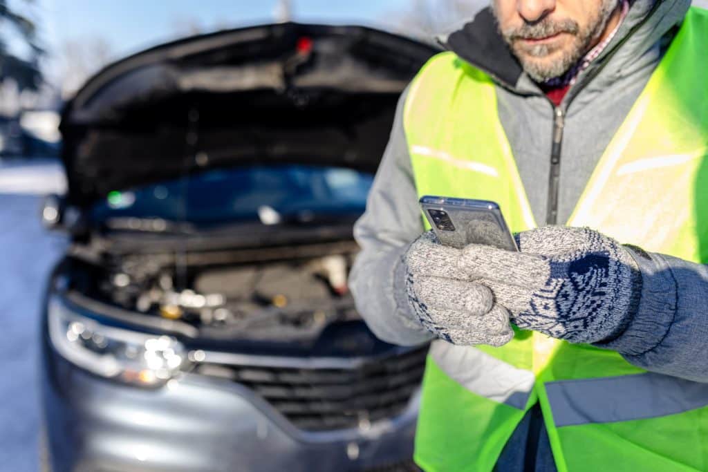 Mann hält Smartphone in der Hand, bereit ihr Auto bei motorschaden-verkaufen.com zu verkaufen